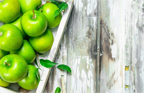 绿色多汁的整个苹果在一个木箱。在一个白色的木制背景。绿色多汁的整个苹果在一个木箱。