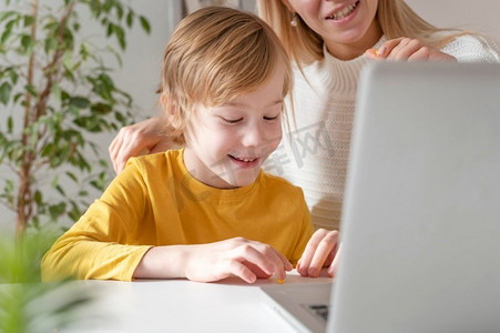 微笑的母亲儿子使用笔记本电脑的家