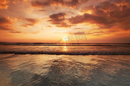 从巴厘岛双六海滩的阳光明媚的日落，海浪和五颜六色的云。阳光海滩日落