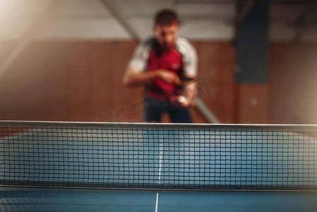 乒乓球网，选择性焦点，背景男球员。乒乓球训练室内