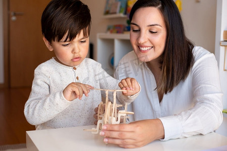 Liltle学龄前儿童玩木头3D拼图和教师教育者的帮助。家庭疑难解答。学习型社区。蒙特梭利学派