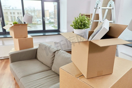 维修，搬家和房地产概念-沙发和瓦楞纸箱的东西在新家。新家的沙发和装满东西的瓦楞纸箱