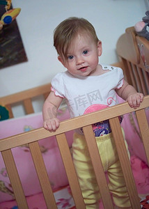 教育摄影照片_可爱的小一岁的婴儿玩玩具在床上，而使第一步和学习走路