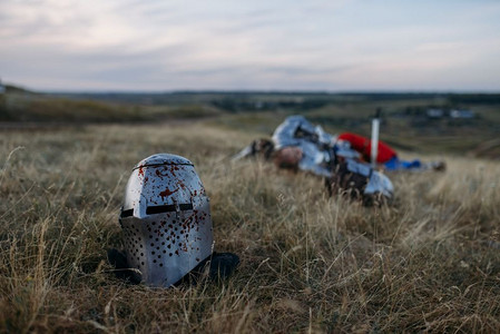 铠甲骑士摄影照片_血头盔，背景中死去的中世纪骑士，伟大的比赛。装甲古代战士在装甲摆在领域