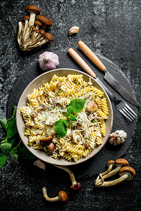 食物面条摄影照片_在一碗蘑菇和大蒜中加入意大利面条。在乡村背景下。在一碗蘑菇和大蒜中加入意大利面条。