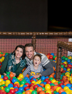 愉快的家庭享受空闲时间年轻的父母和孩子玩在游泳池与五颜六色的球在儿童游戏室
