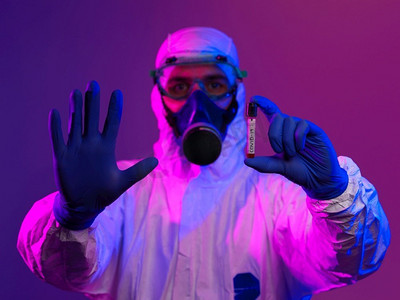 冠状病毒，医生拿着阳性新冠病毒血样管。佩戴生物危害流行病防护口罩、防护服、发光。