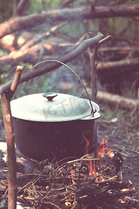 燃烧的森林摄影照片_在徒步旅行中露营燃烧的篝火的火的旅游水壶。在森林里用木柴做饭。