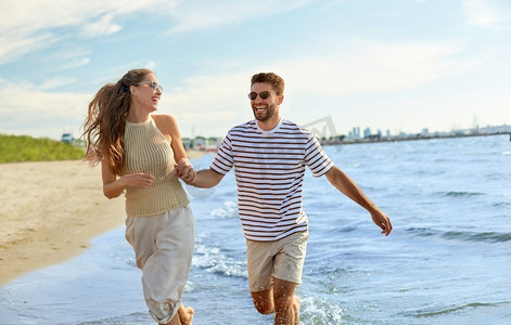 暑假和人们概念快乐的情侣沿着海滩跑步。幸福的情侣沿着夏日海滩奔跑