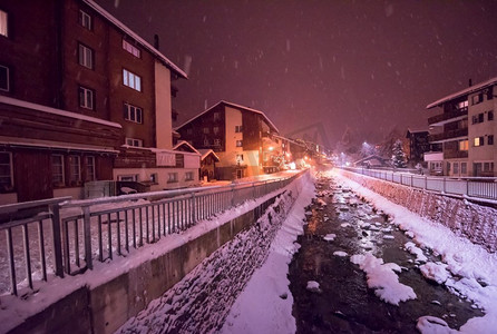 在寒冷的冬夜，阿尔卑斯山村的雪街上，