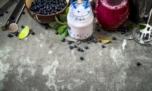 蓝莓果汁摄影照片_蓝莓配蓝莓冰沙和果汁在石桌上。蓝莓冰沙和果汁