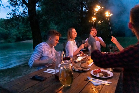 一组愉快的朋友野餐法国晚餐聚会户外在暑假假期在美丽的自然附近的河