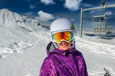 戴着滑雪护目镜的年轻女子在户外，背景是法国阿尔卑斯山被白雪覆盖。法国梅里贝尔