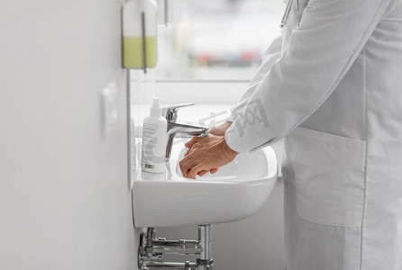 水槽洗手摄影照片_卫生保健，卫生和人的概念—医生在医院洗手池洗手。医生在医院洗手池洗手