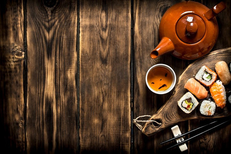 寿司和卷配凉茶。在一张木桌上..寿司和卷配凉茶。