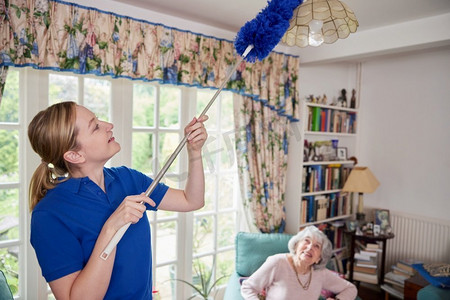女性家庭帮助打扫房子，因为她灰尘和与高级妇女交谈