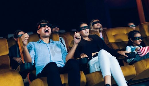 一群人在电影院里戴着 3d 眼镜看电影,有兴趣地看着屏幕,兴奋地吃着爆