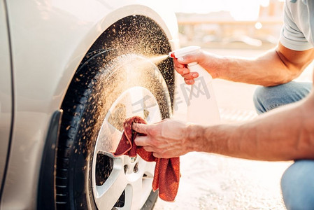 男性手用车边清洁器清洁磁盘，洗车。洗车站