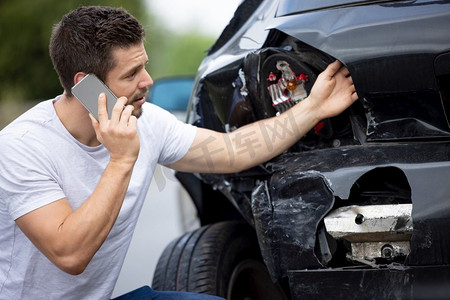 车祸后驾车受损的男性司机不高兴，用手机给保险公司打电话