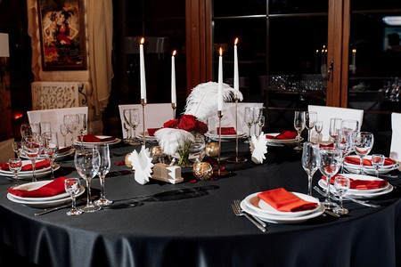 用燃烧的蜡烛装饰桌子，用黑色、红色和白色色调装饰
