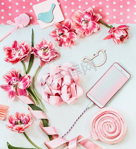 智能手机与粉红色的花和丝带在白色桌子。俯视图。母亲节。生日空白屏幕。问候和技术。拷贝空间