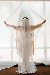 一个女孩，新娘高兴地打开了一扇大窗户的窗帘