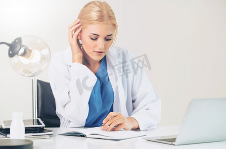 医院或保健机构的女医生在办公室桌子上做医疗报告。医院里的医生在写医疗报告。