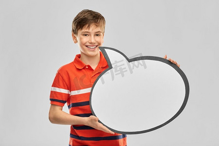 卡通说话气泡摄影照片_沟通和人的概念—微笑的男孩拿着空白的讲话气泡在灰色背景。男孩拿着讲话泡泡