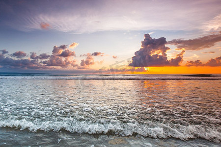 令人惊叹的日落形成了巴厘岛双六海滩的海浪和五颜六色的云彩。巴厘岛海滩上令人惊叹的日落