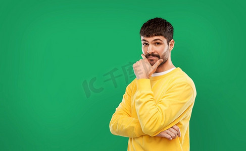 人概念—年轻人在黄色运动衫思考在翡翠绿色背景穿着黄色运动衫的年轻人