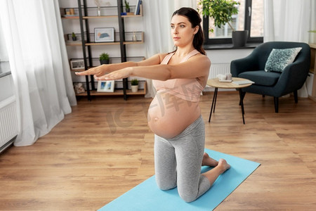 运动，健身和怀孕概念—快乐的孕妇在家里锻炼。快乐的孕妇做运动在家里