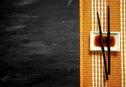 寿司用筷子蘸酱油。在一个黑色的木背景。寿司用筷子蘸酱油。