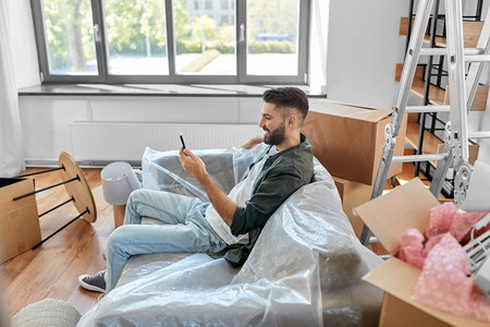 移动，人和房地产概念—人与智能手机和盒子在新家。带智能手机和盒子的男子搬进新家