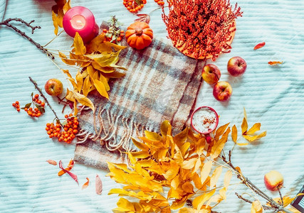 秋天的生活方式框架与南瓜，黄色的秋叶，卡布奇诺和蜡烛在白色的毯子上。查看。平铺