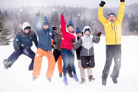 在山林中进行团队建设时，年轻快乐的商人们在雪地里享受着雪花环绕的冬日的群像