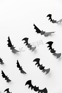 黑色蝙蝠摄影照片_万圣节，装饰和可怕的概念—群黑色纸蝙蝠飞行在白色背景。一群黑色纸蝙蝠在白色背景