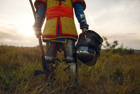 中世纪骑士在盔甲持有斧头和头盔，伟大的比赛。装甲古代战士在装甲摆在领域