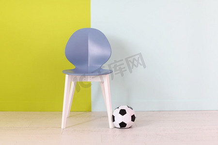 现代蓝色椅子和足球在一个蓝色绿色背景前面家装饰的概念