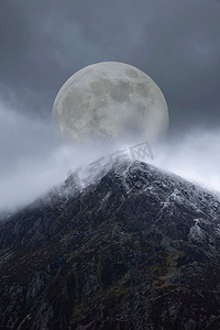月球山脉摄影照片_山脉上方的超级月亮美丽的数字合成图像为戏剧性的风景图像赋予了非常超现实的奇幻外观