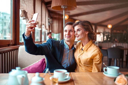 相爱的情侣在餐厅的手机摄像头前拥抱并自拍。男人和女人幸福地在一起。爱侣拥抱并在手机摄像头前自拍