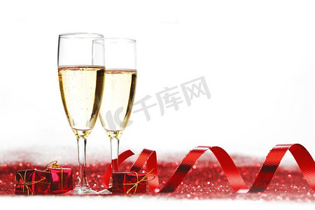 玻璃与香槟和礼物在红色闪光隔绝在白色背景。香槟闪烁