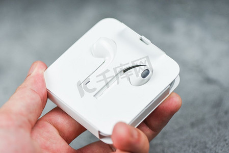 白色无线蓝牙耳机或耳机智能手机耳机在塑料存储箱隔离在手，选择性焦点