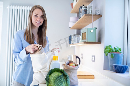 购物归来的妇女用免塑料袋打开食品杂货的肖像