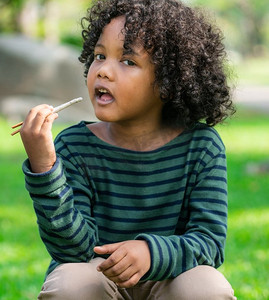 快乐的非裔美国儿童吃零食棒在公园。儿童营养观快乐的非裔美国儿童吃零食棒。