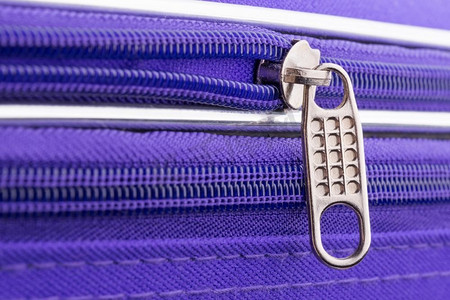 一个拉链的宏观显示拉标签和链在一个紫色的行李箱准备安全的假日旅行