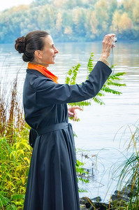 优雅的高级女商人与一个数码相机，一个包和橙色围巾，拍照沿河