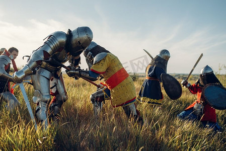 中世纪的骑士穿着盔甲和头盔，用剑和斧头战斗，伟大的战斗。装甲古代战士在装甲摆在领域