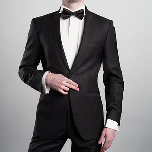 男性黑色摄影照片_照片时尚的男子在优雅的黑色西装与领带。时尚的年轻模特在摄影工作室摆姿势。豪华的晚上吸烟与白色衬衫。
