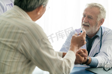 资深男医生在医院办公室与老年病人交谈。医疗保健和医生员工服务理念。