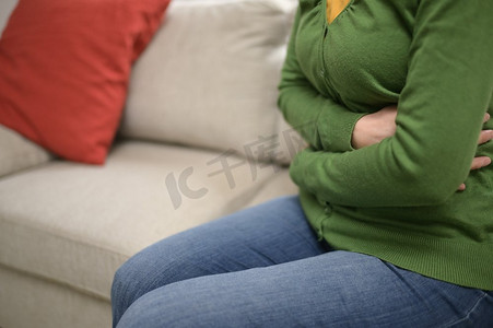 卵巢癌摄影照片_女人手在沙发上的前胃疼痛